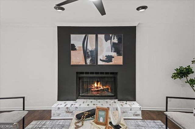 details featuring wood-type flooring, a brick fireplace, ceiling fan, and ornamental molding