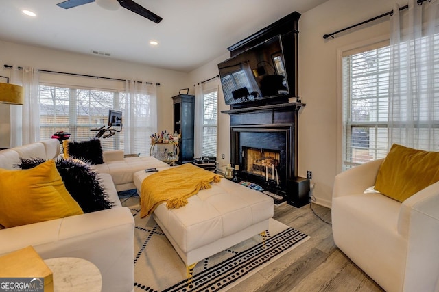 living room featuring light hardwood / wood-style floors, a large fireplace, and ceiling fan