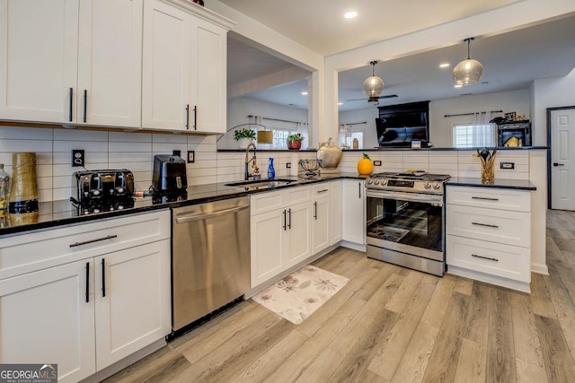 kitchen featuring sink, tasteful backsplash, stainless steel appliances, light hardwood / wood-style floors, and white cabinets