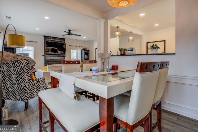 dining space featuring decorative columns, dark wood-type flooring, and ceiling fan