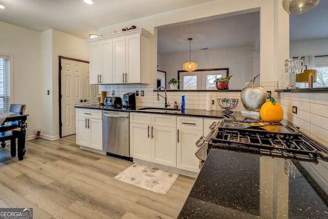 kitchen with hanging light fixtures, appliances with stainless steel finishes, sink, and white cabinets