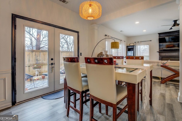 dining space with french doors, light hardwood / wood-style floors, and a wealth of natural light