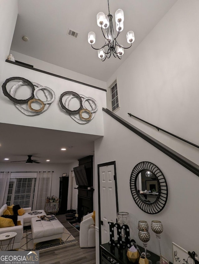 stairway featuring ceiling fan with notable chandelier and wood-type flooring