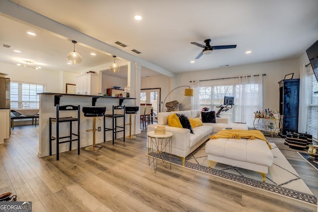 living room featuring ceiling fan, a wealth of natural light, and light wood-type flooring