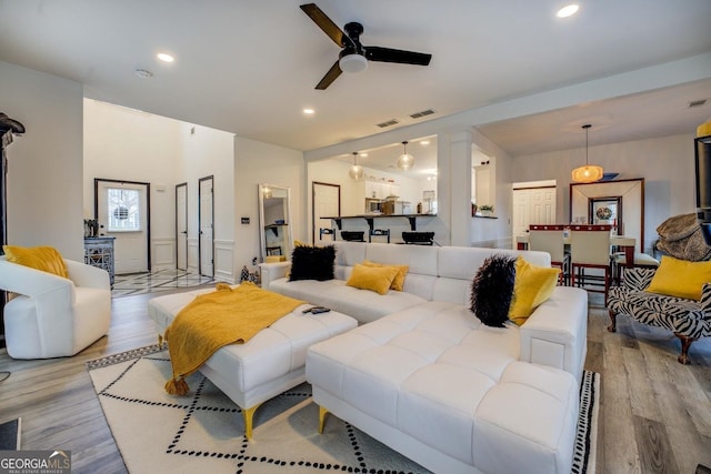 living room featuring light hardwood / wood-style flooring, decorative columns, and ceiling fan