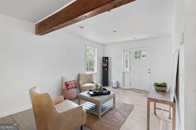 living room featuring beamed ceiling, light wood-type flooring, and a healthy amount of sunlight