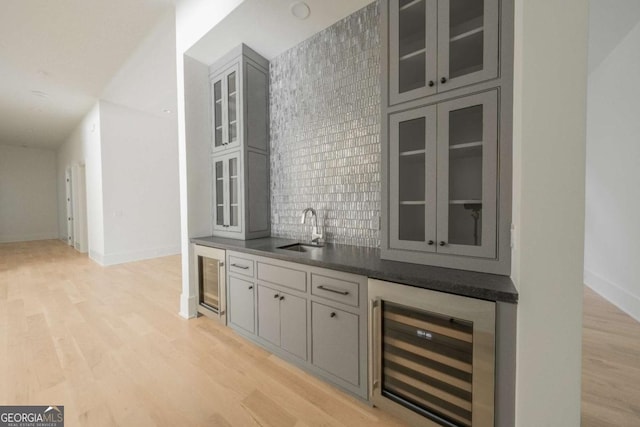 bar featuring backsplash, gray cabinets, sink, and beverage cooler