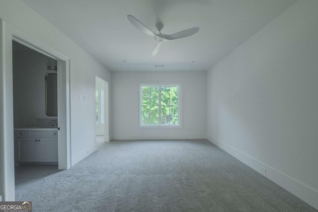 unfurnished bedroom featuring connected bathroom, ceiling fan, sink, and light colored carpet