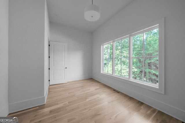 spare room with light hardwood / wood-style flooring and lofted ceiling