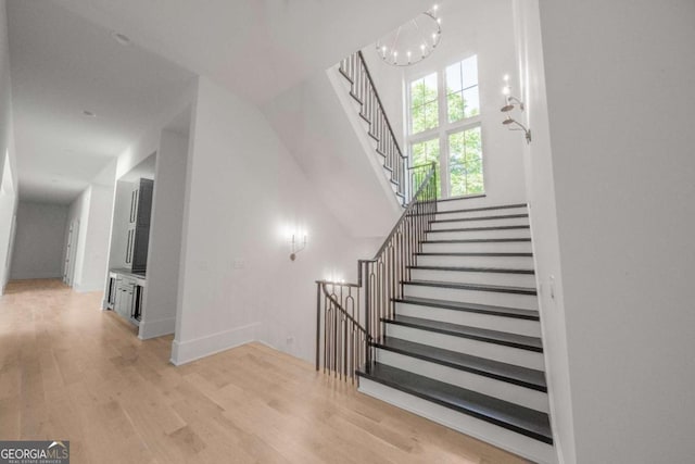 stairway with wood-type flooring and an inviting chandelier