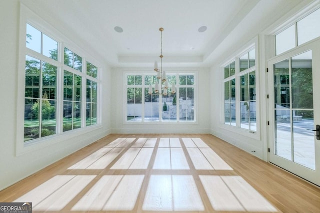 unfurnished sunroom with a raised ceiling, a wealth of natural light, and an inviting chandelier