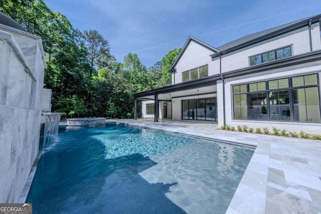 view of pool with an in ground hot tub, pool water feature, and a patio area