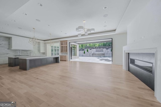 unfurnished living room with light wood-type flooring and a chandelier