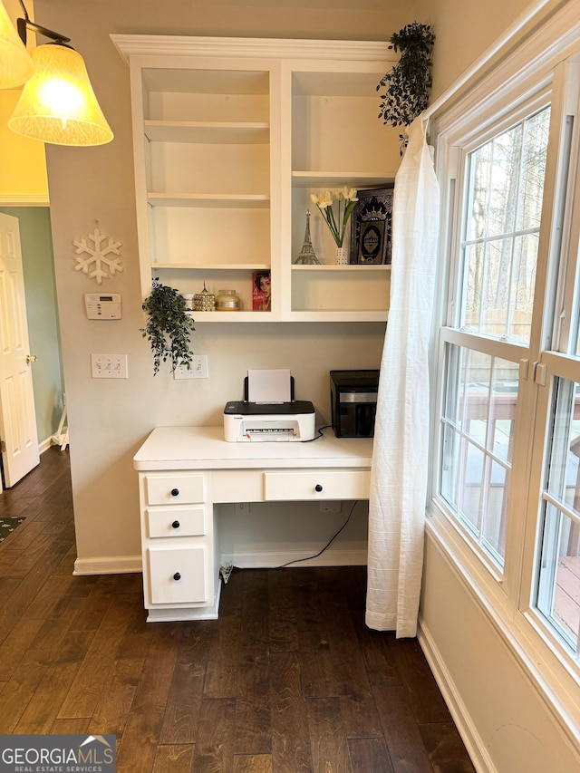 office space with built in desk and dark wood-type flooring