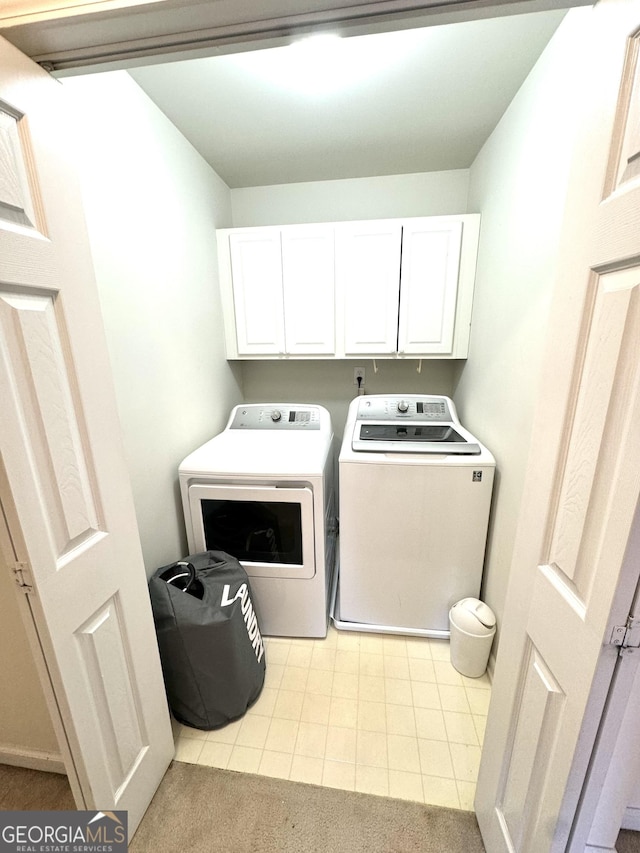 laundry room with washer and clothes dryer, light tile patterned flooring, and cabinets