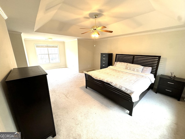 carpeted bedroom with ceiling fan, a raised ceiling, and ornamental molding