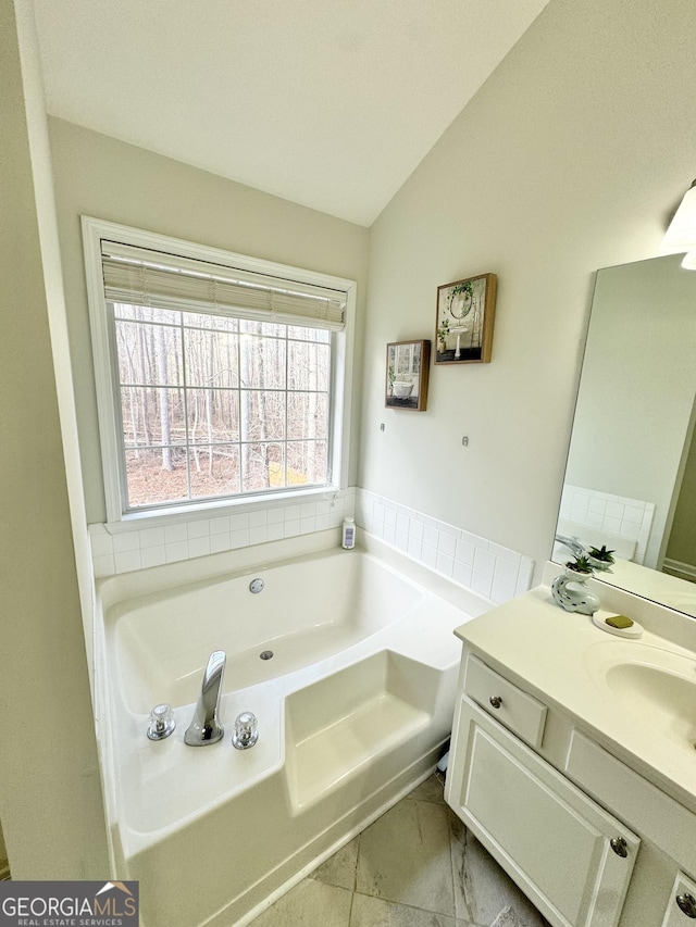 bathroom with plenty of natural light, lofted ceiling, a tub to relax in, and vanity