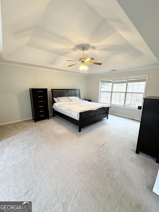 carpeted bedroom featuring ceiling fan, crown molding, and a tray ceiling