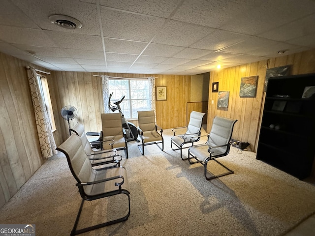 interior space with a paneled ceiling, wooden walls, and carpet