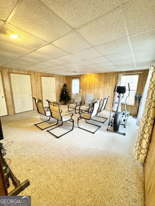 workout area with a paneled ceiling, wood walls, and carpet floors