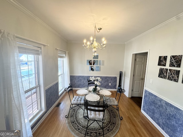 dining space featuring dark hardwood / wood-style flooring, ornamental molding, and a notable chandelier