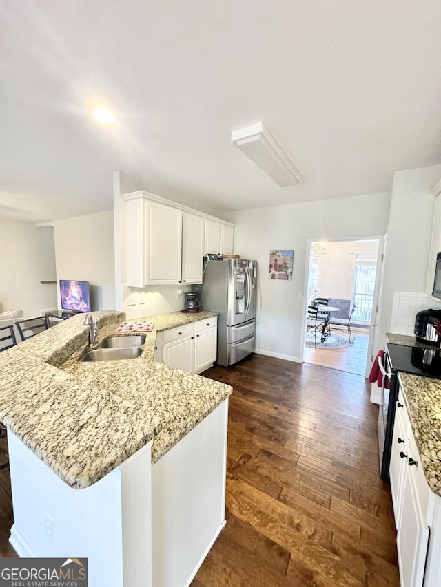 kitchen featuring kitchen peninsula, appliances with stainless steel finishes, sink, white cabinets, and dark hardwood / wood-style floors