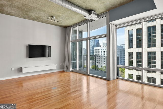 unfurnished living room with wood-type flooring and floor to ceiling windows