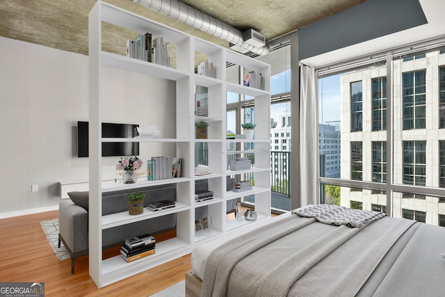 bedroom with a wall of windows and hardwood / wood-style flooring