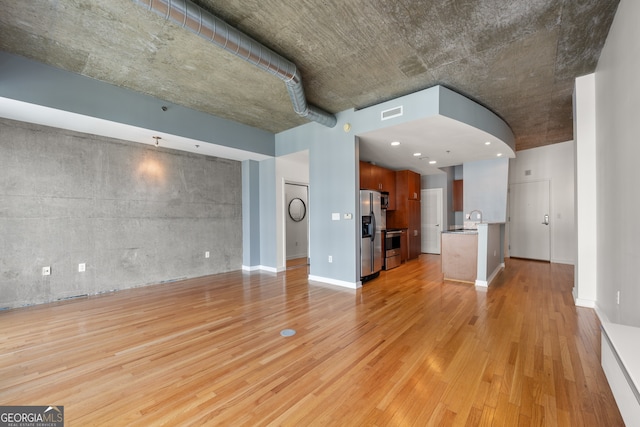 unfurnished living room featuring light wood-type flooring and sink