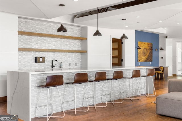 bar with backsplash, hardwood / wood-style floors, and pendant lighting