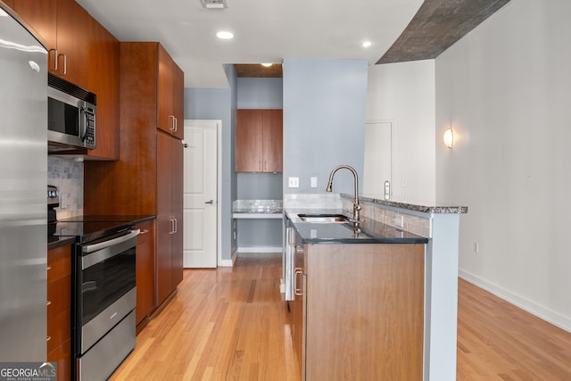 kitchen with backsplash, sink, stainless steel appliances, and light hardwood / wood-style floors