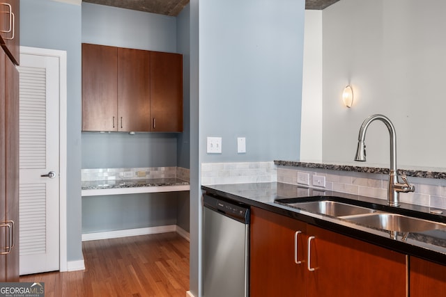 kitchen featuring tasteful backsplash, sink, dark stone countertops, dishwasher, and light hardwood / wood-style floors