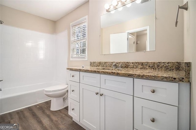 full bathroom featuring washtub / shower combination, wood-type flooring, vanity, and toilet