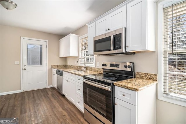 kitchen featuring white cabinets, appliances with stainless steel finishes, a wealth of natural light, and light stone countertops