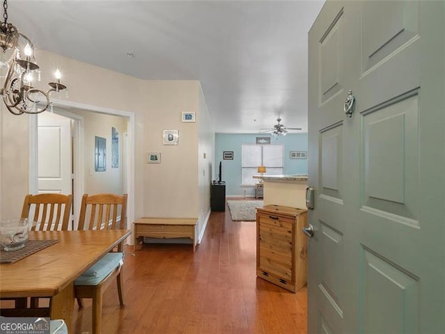 dining space with wood-type flooring and ceiling fan with notable chandelier