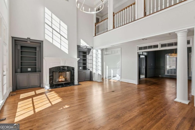 unfurnished living room with a high end fireplace, hardwood / wood-style floors, and a high ceiling