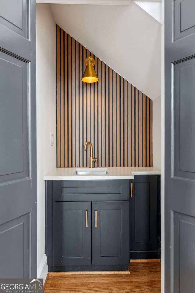 bar featuring gray cabinetry, sink, and light wood-type flooring