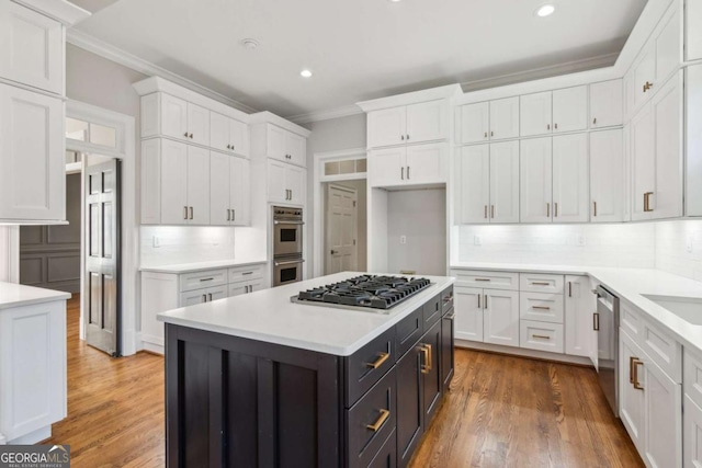 kitchen with stainless steel appliances, a kitchen island, light hardwood / wood-style flooring, backsplash, and white cabinets