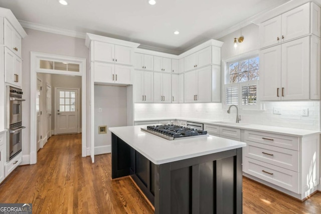 kitchen with backsplash, sink, appliances with stainless steel finishes, a kitchen island, and white cabinetry