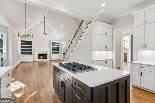 kitchen with backsplash, white cabinetry, stainless steel gas cooktop, and ceiling fan