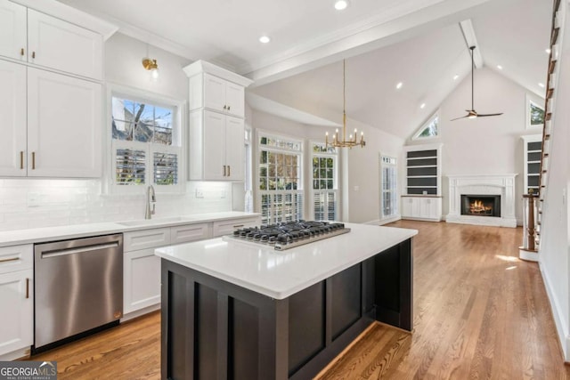 kitchen with decorative backsplash, stainless steel appliances, sink, white cabinets, and a kitchen island