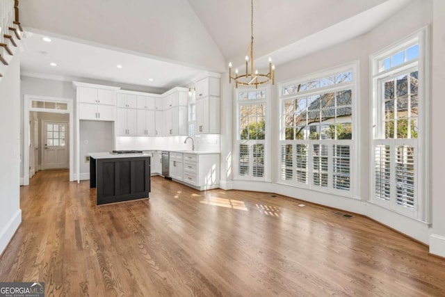 interior space with a center island, white cabinets, hanging light fixtures, decorative backsplash, and a chandelier