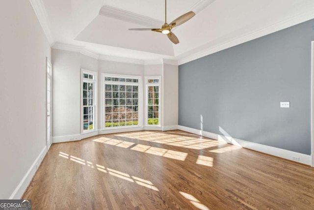 unfurnished room featuring a tray ceiling, ceiling fan, crown molding, and light hardwood / wood-style floors