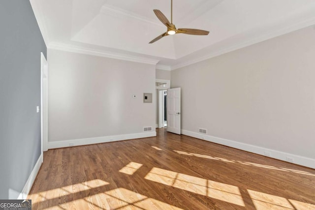 unfurnished room with a tray ceiling, ceiling fan, crown molding, and hardwood / wood-style flooring