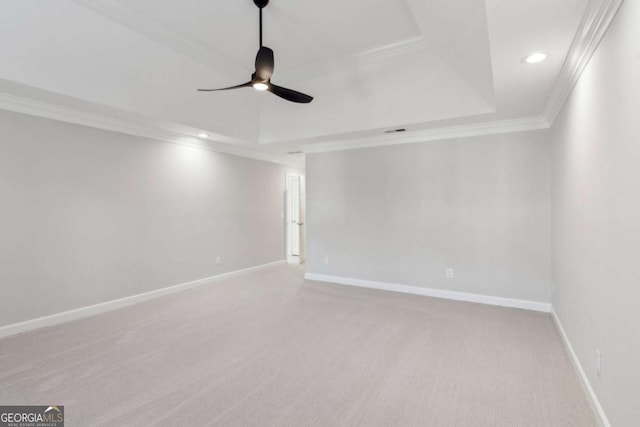 carpeted empty room featuring a raised ceiling, ceiling fan, and ornamental molding