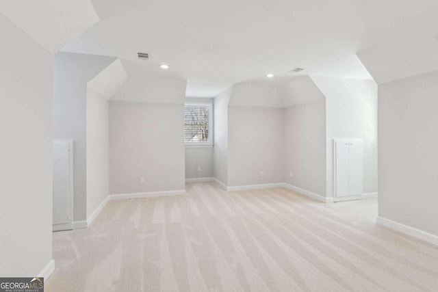 additional living space featuring light carpet and vaulted ceiling