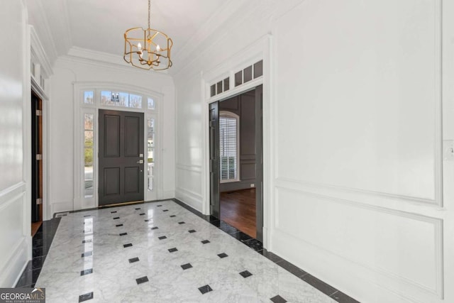 entrance foyer with ornamental molding and an inviting chandelier