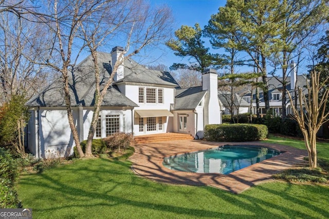 back of property featuring french doors, a patio, and a lawn