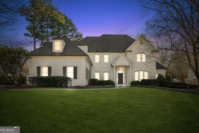 french country inspired facade featuring a yard