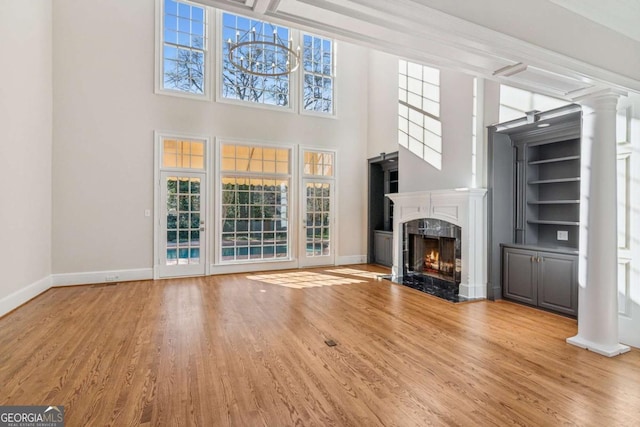 unfurnished living room with light hardwood / wood-style floors, a premium fireplace, and a towering ceiling